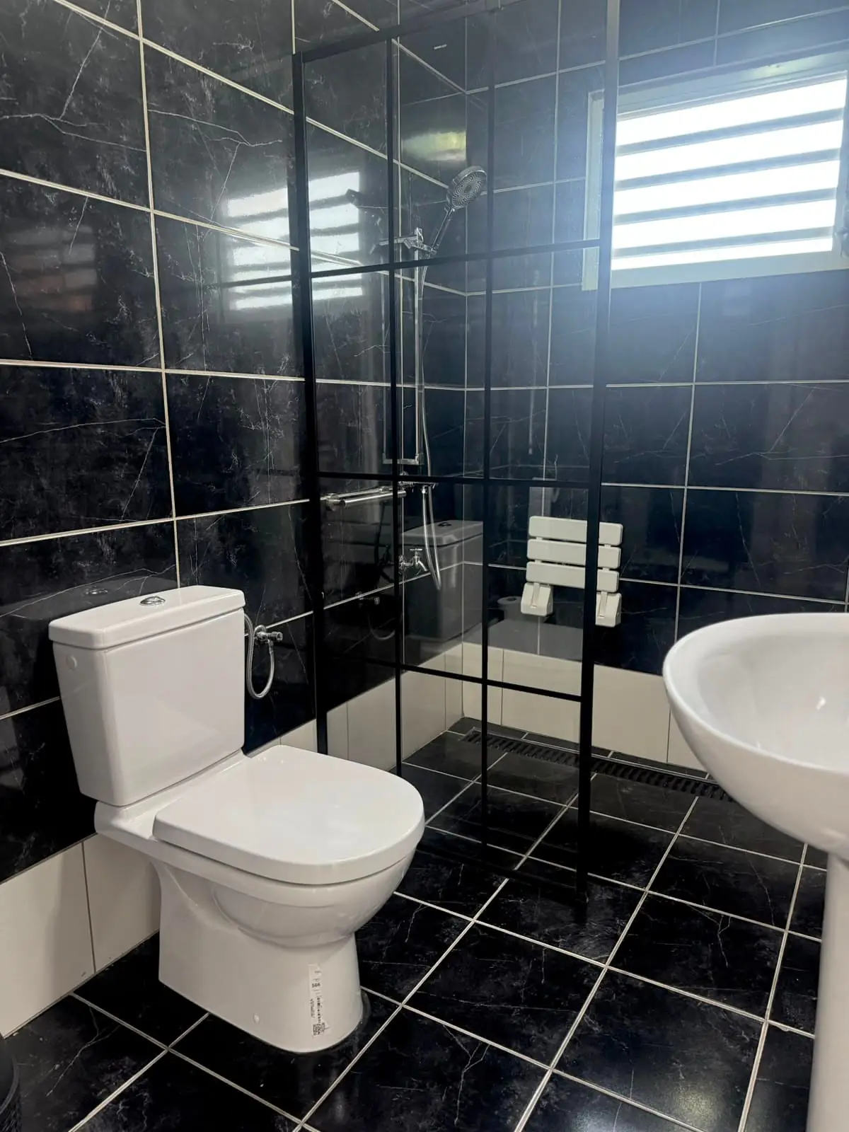 De badkamer van Yeva, met inloopdouche, opklapbaar douchezitje en beugel.